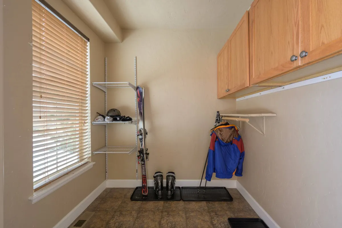 This interior image features a mudroom equipped with ski equipment, shelves, and storage cabinets. The area is clearly functional, with space specifically dedicated to storing outdoor sports gear and preparing for activities like skiing. The setting is practical but welcoming, communicating readiness for both winter and summer adventures.