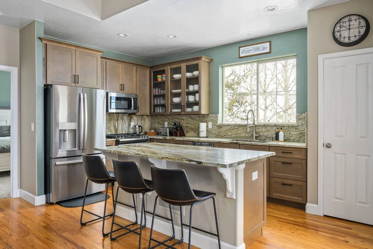 A spacious, modern kitchen featuring a large island with ample seating, stainless steel appliances, and a prominent window that lets in natural light. The layout is ideal for family meals and lively gatherings, with plenty of room for cooking and socializing.