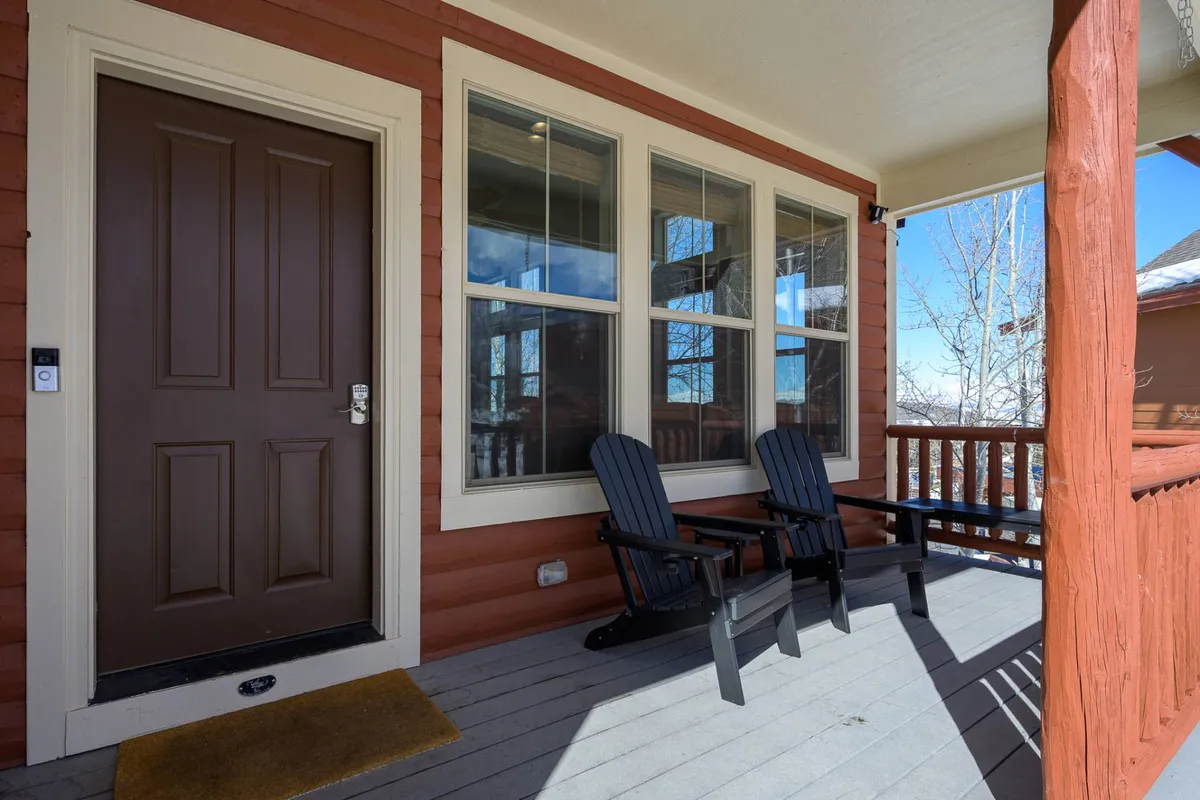 A close-up of the front entrance to the house, featuring comfortable rocking chairs and windows that offer a glimpse inside. The inviting setup hints at moments of relaxation and connection just outside the front door.