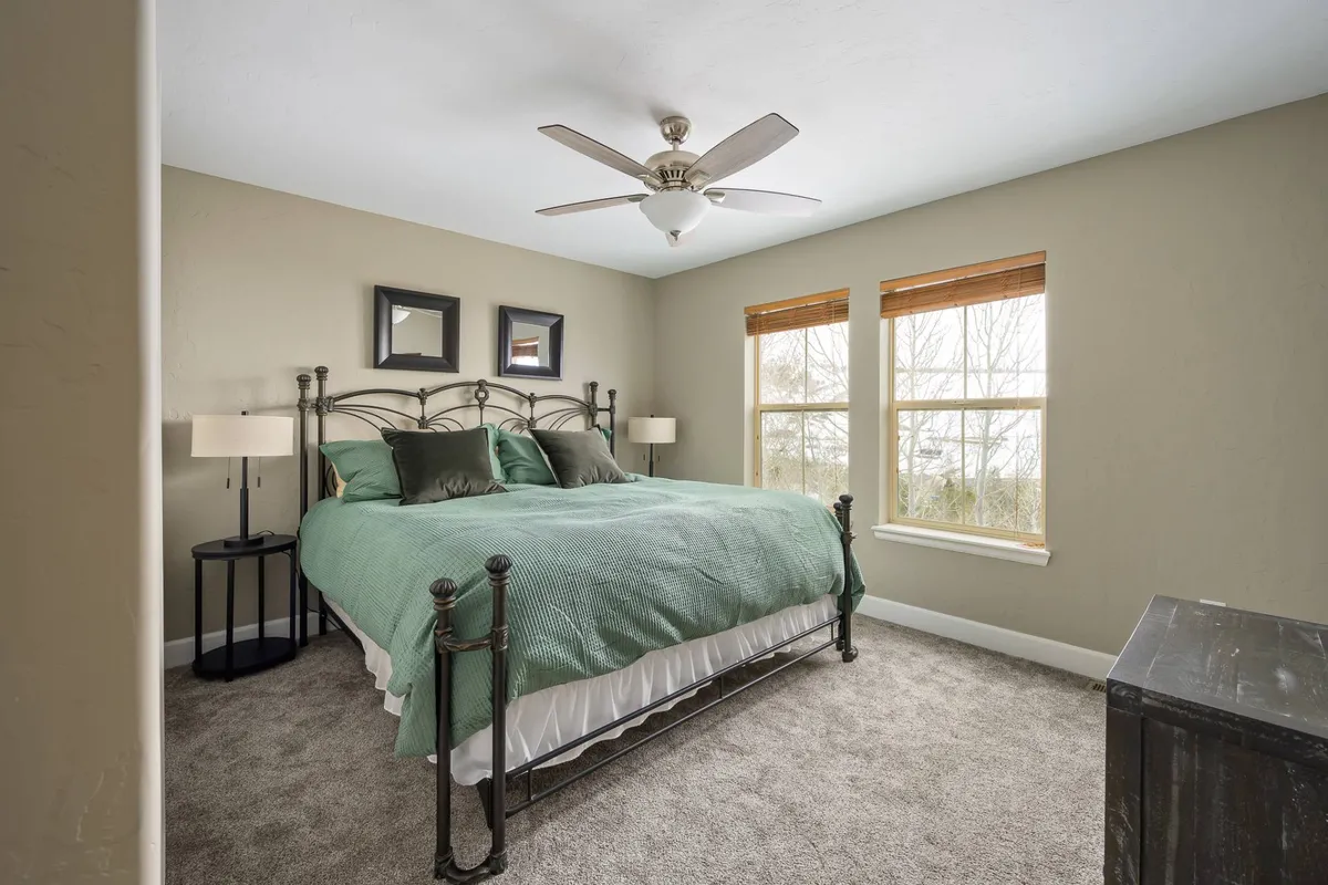 A tranquil bedroom with teal and white bedding, two bedside lamps, and large windows offering a soft glow. The arrangement and decor suggest a cozy, peaceful place to unwind after a day of adventure.